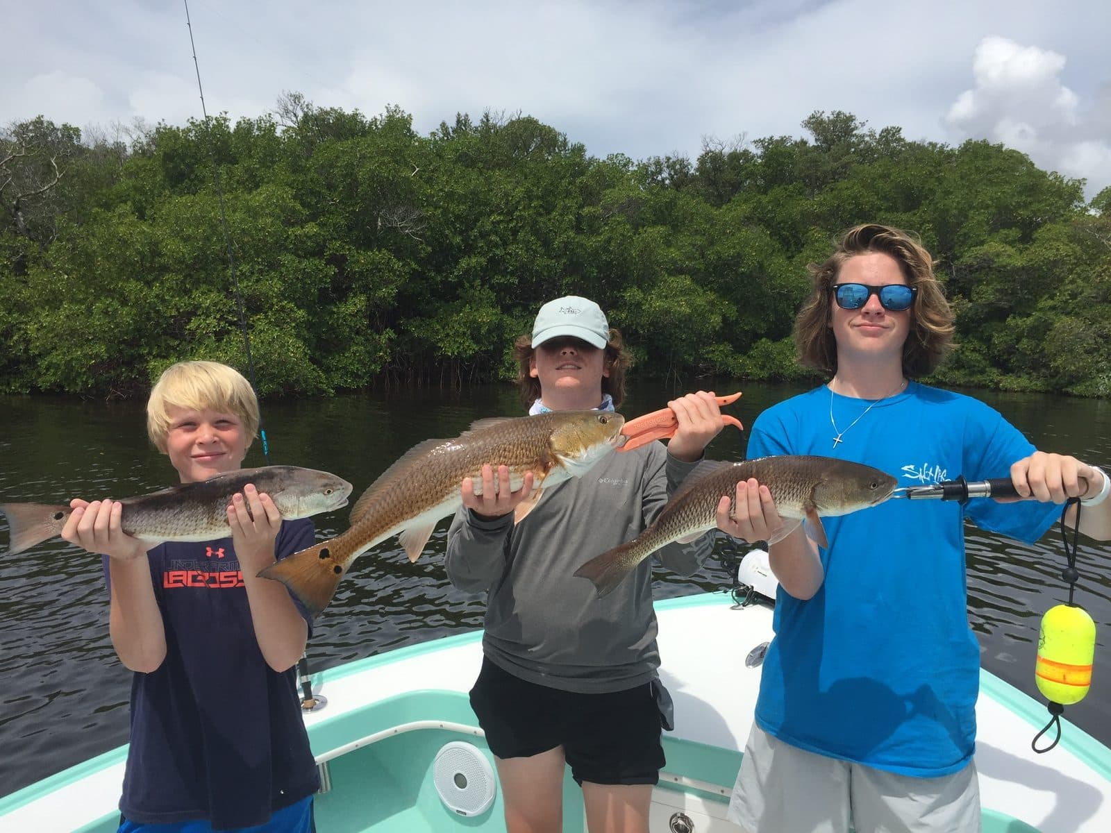Three young anglers each holding a redfish