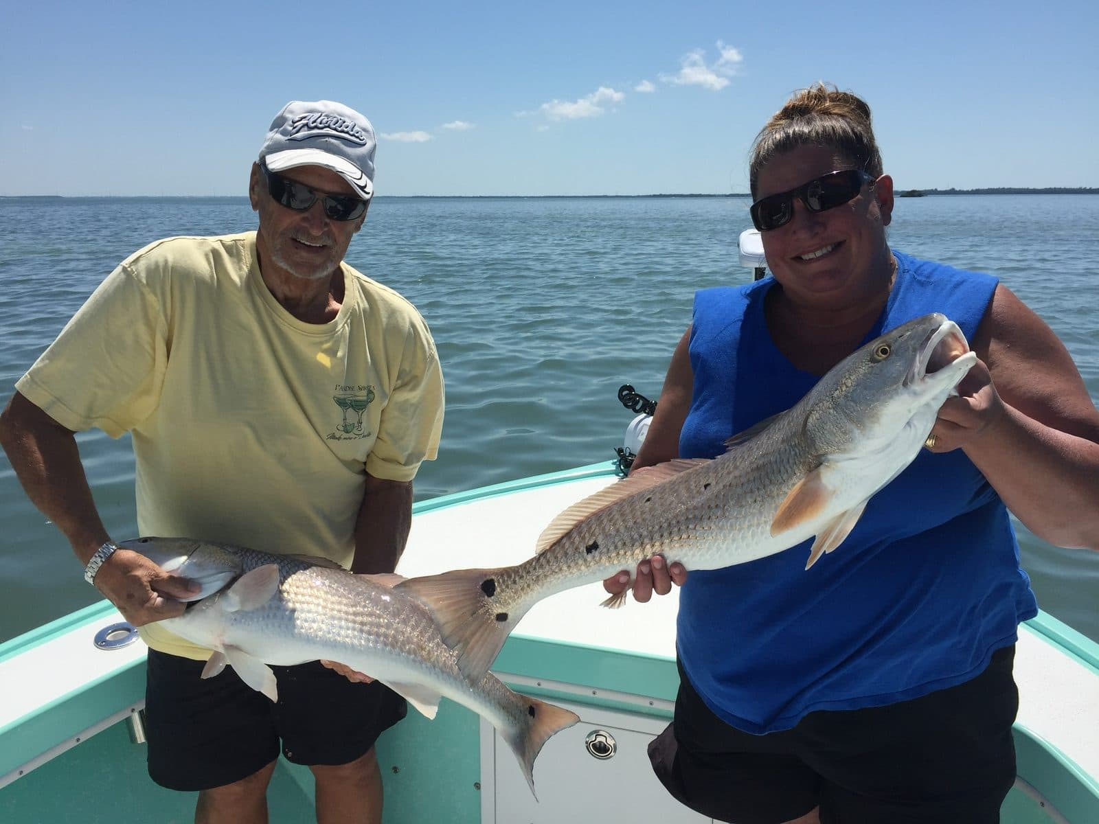 Two anglers each holding a redfish