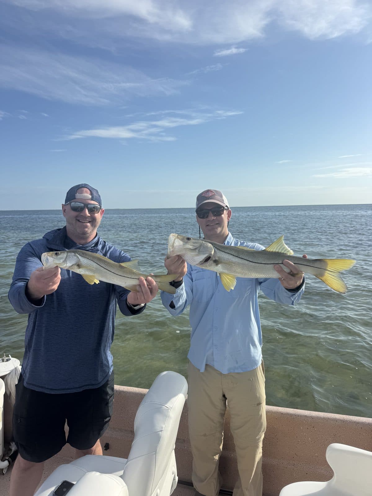 Two anglers each holding a snook