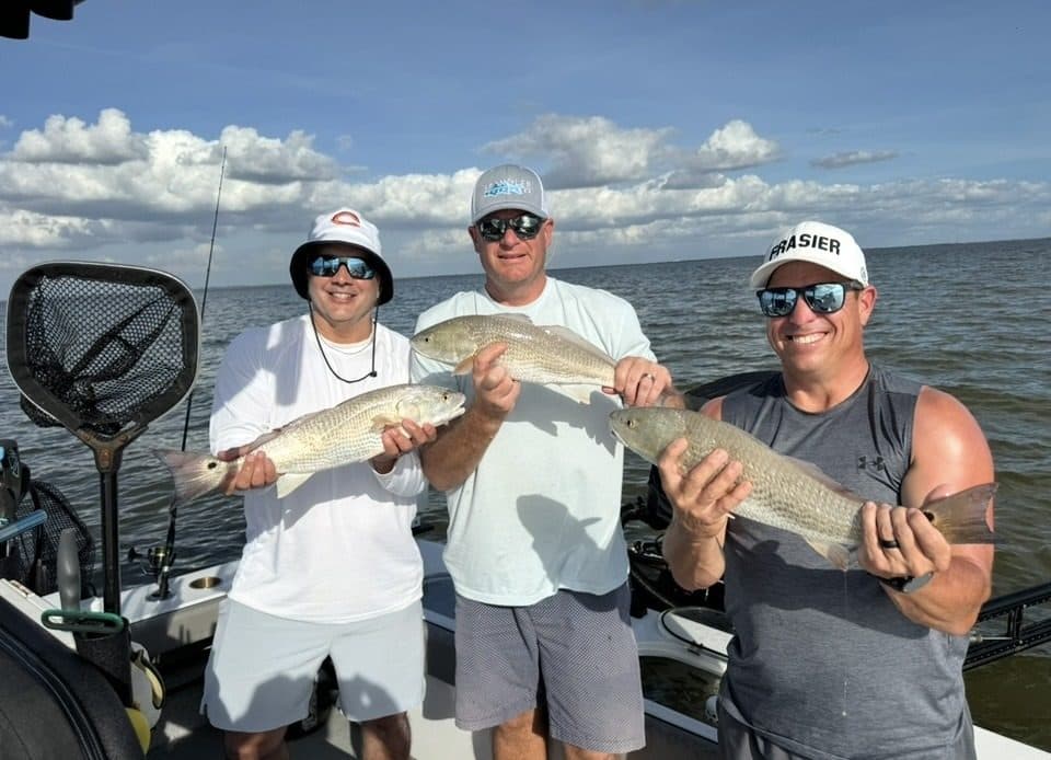 Three anglers holding their catch on the bay boat