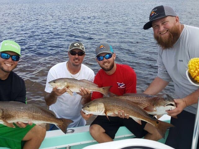 Four anglers holding redfish